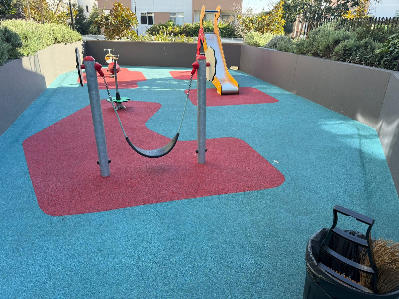 Shared play area with outdoor equipment and safety surfacing.