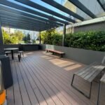 Outdoor shared BBQ area with seating and landscaped surrounds.