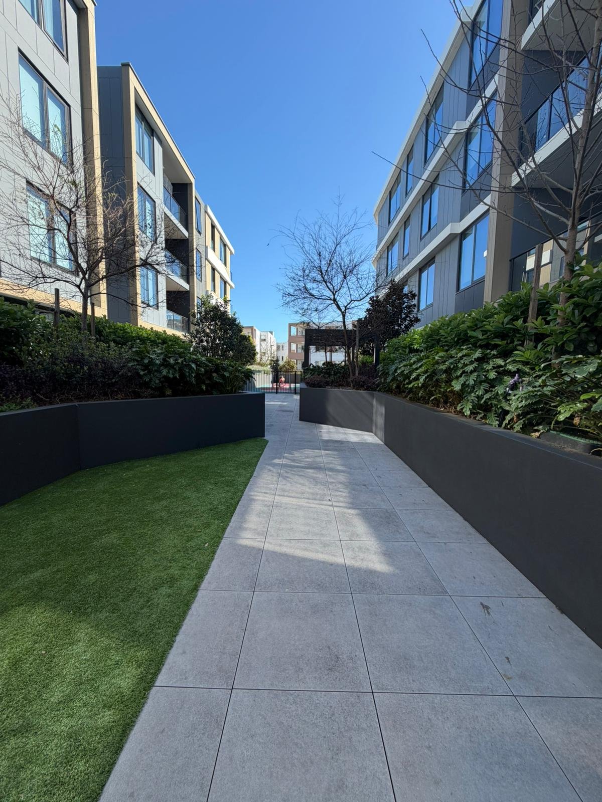 Apartment building courtyard with a paved walkway and landscaped garden beds.